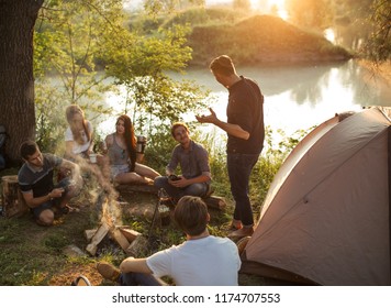 guy is telling campfire stories to the travelers in the nature at sunset