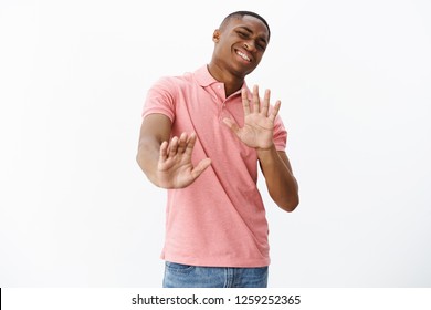 Guy think he pass. Uninterested african american man unwilling to participate in party raising hands near chest in no and refusal gesturing bending backwards with awkward smile while rejecting offer