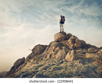 Guy with a travel backpack on the top of a boulder - Powered by Shutterstock