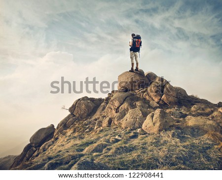 Guy with a travel backpack on the top of a boulder