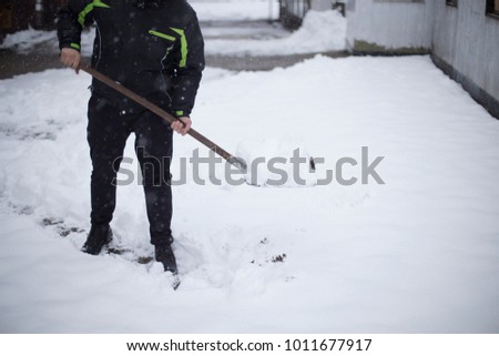 Guy trowing the snow of his shovel. 