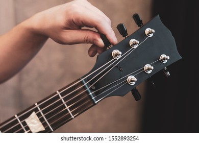 guy tuning his guitar. Guitar neck and tuning pegs