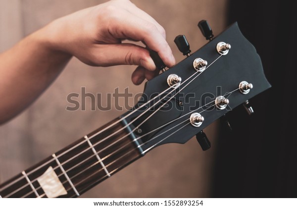 guy tuning\
his guitar. Guitar neck and tuning\
pegs