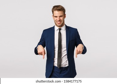 Guy Turn Your Attention At Something Awful And Unpleasant. Attractive Blond Bearded Businessman In Classic Suit, Pointing Down And Grimacing From Aversion, Seeing Creepy Thing, White Background