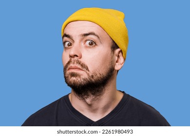 A guy with an uncertain expression, his face contorted in a grimace, captured in a studio shot while looking at the camera. Doubtful and Funny A Studio Shot of a Man's Facial Expressions - Shutterstock ID 2261980493
