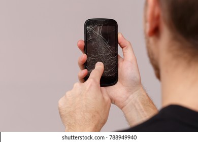 A Guy Uses A Broken Mobile Phone. Close-up. Back View.