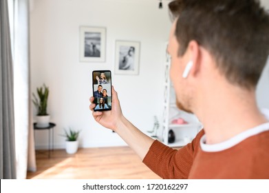 A Guy Using App On A Smartphone For Video Meeting With Coworkers, Friends. He Is Talking Via Video Call With A Few People. Close-up Back View