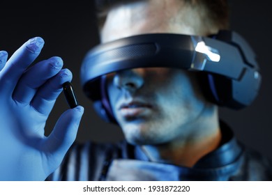 Guy verwendet VR-Helm. Augmented Reality, Zukunftstechnologie, Spielkonzept. Blaues Neonlicht. Mann, der eine futuristische Pille hält.
