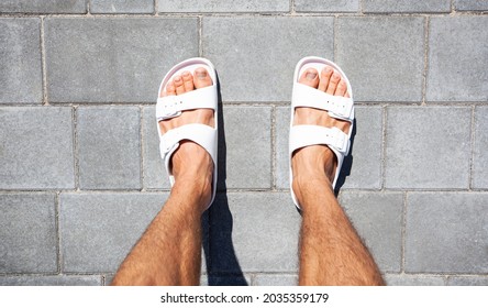 Guy walking on paving slabs in white flip flops  