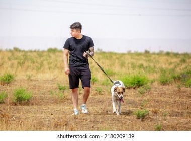 The Guy Walks The Dog On The Lawn In The Park. A Man Plays With A Pet On The Street. An Animal Welfare Volunteer Takes Care Of Homeless Animals At A Shelter. Kazakhstan, Almaty - June 20, 2022