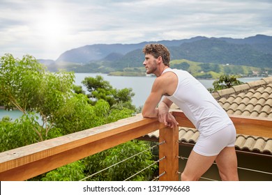 Guy watching sunrise from balcony in underwear