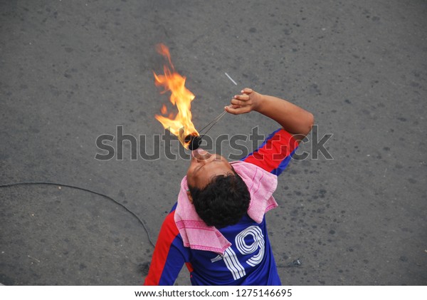 a guy wearing\
football shirt want to demonstrate eating hot flame, jakarta,\
indonesia. photo taken in may\
2011