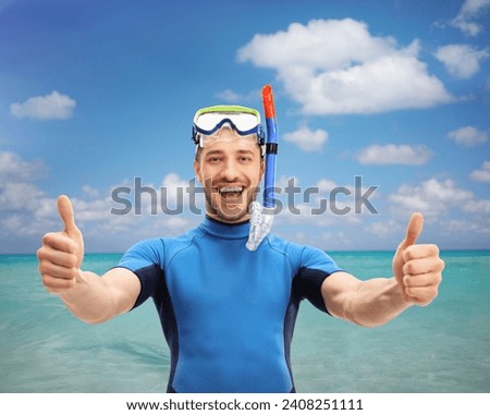 Guy in a wetsuit with a diving mask making a thumbs up gesture by the sea 商業照片 © 