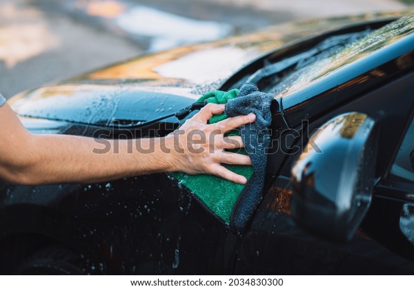 The guy wipes the car\
with soap rag.