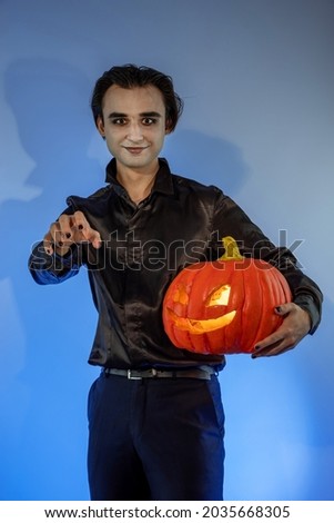 Guy witcher celebrating a Halloween party or Day of the Dead. A gothic-punk young man with a face painted in the make-up of a wizard, vampire, devil holding a carved pumpkin Jack-o'-lantern Stock photo © 