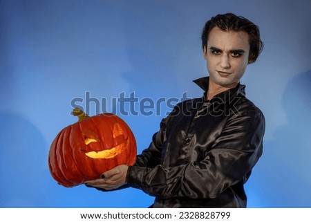 Guy witcher celebrating a Halloween party or Day of the Dead. A gothic-punk young man with a face painted in the make-up of a wizard, vampire, devil holding a carved pumpkin Jack-o'-lantern Stock photo © 