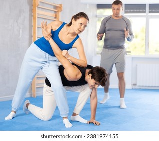 Guy and woman in sparring practice technique practicing basic attacking movements and maneuvers. Class self-defense training in presence of experienced instructor