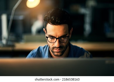 IT Guy Working With Computer Late At Night, Searching Online While Planning, Thinking Strategy Or Typing Out Deadline. Business Man With Glasses Looking Serious And Concentrating In Office