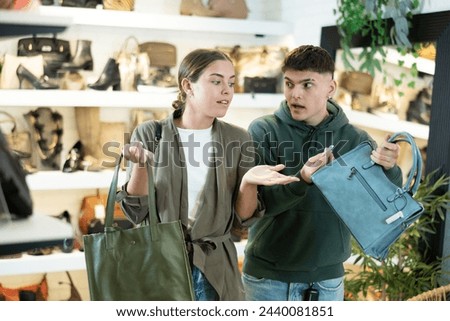 Guy with young female friend in store eye windowshopping product she likes and tactilely checks authenticity and naturalness 