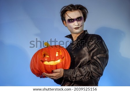 Guy zombie celebrating a Halloween party or Day of the Dead. A gothic-punk young man with a face painted in the make-up of a wizard, vampire, devil holding a carved pumpkin Jack-o'-lantern Stock photo © 