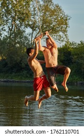 Guys Jumping Into A River Using Rope Swing