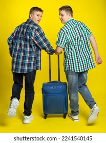 guys with a suitcase. Studio colored background. blue yellow. Cheerful boys, students gathered for study or vacation. teenager laughs. - Shutterstock ID 2241540145