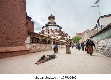Gyantse - May 18, 2013: Unidentified tibetan pilgrims circumambulate Pelkor Chode Monastery by performing full body prostrations or walking around the monastery.