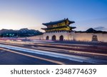 Gyeongbokgung palace in Seoul City, South Korea during a blue hour with light trails of passing traffic visible in foreground. Korean text translated to english says Gwanghwamun, whis is name of gate.