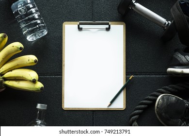 Gym Background With Mockup Clipboard Note Plan For The Workout.Detail With Healthy Food Banana And Water And Fitness Equipment