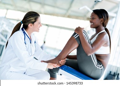 Gym doctor with a patient checking her ankle  - Powered by Shutterstock