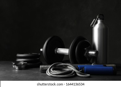 Gym equipment and accessories on stone floor against dark background