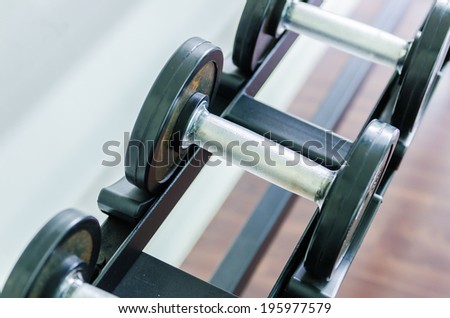 Gym equipment background with close up selective focus to a dumbbell