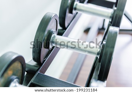 Gym equipment background with close up selective focus to a dumbbell
