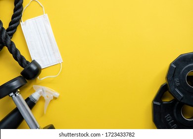 Gym Equipment With Mask And Protection Stuff On Yellow Background: Stay Safe Workout From Home Concepts