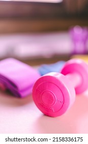 Gym Equipments On A Pink Yoga Mat. Blue Rubber Band, Blue And Pink Resistance Band And Pink Dumbell