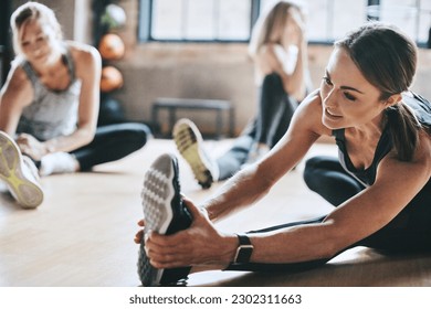 Gym, exercise and women stretching, workout and training for wellness, healthy lifestyle and balance. Female people, athletes or girls on the floor, practice and sports with progress, focus or energy - Powered by Shutterstock