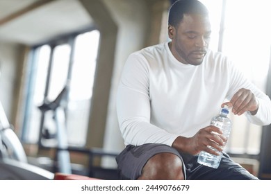 Gym, fitness and black man with water for training recovery, break or body hydration after exercise. Sports, liquid and African athlete with mineral drink for health, wellness and workout balance - Powered by Shutterstock