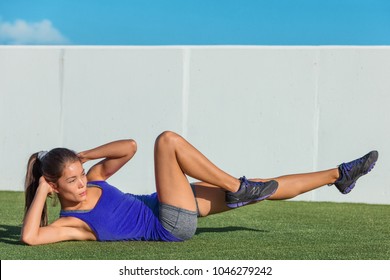 Gym girl doing bicycle crunch exercise on floor grass at home or outdoor fitness centre. Active asian woman training core muscles with sit-ups for belly fat.