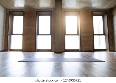 Gym Loft Interior Of Fitness Studio With Blue Yoga Mat, Big Windows And Sunlight, No People. Copy Space