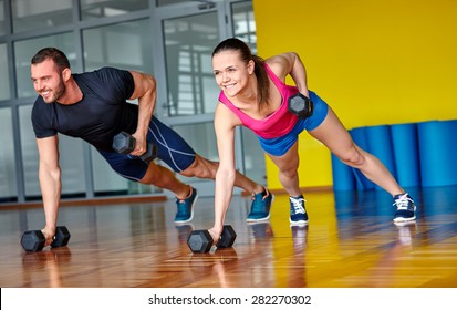 Gym Man And Woman Push-up Strength Pushup With Dumbbell In A Fitness Workout