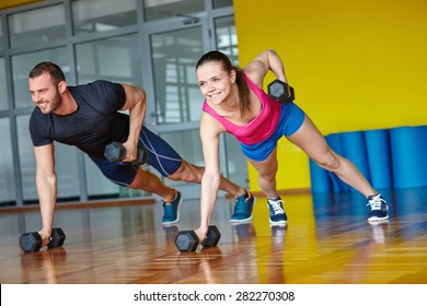 Gym Man And Woman Push-up Strength Pushup With Dumbbell In A Fitness Workout