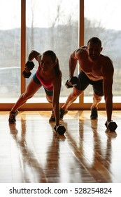 Gym Man And Woman Push-up Strength Pushup With Dumbbell In A Fitness Workout