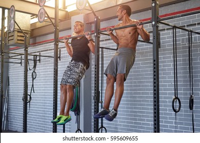 Gym partners buddies doing pull ups in a industrial looking gym, muscular fit lean men exercising - Powered by Shutterstock