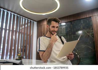 Gym Services. Male Customer Standing At Recepion Desk, Studying Carefully Price List