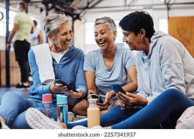 Gym, smartphone and senior women laughing at meme on phone after fitness class, conversation and comedy on floor. Exercise, bonding and happy mature friends checking social media together at workout. - Powered by Shutterstock