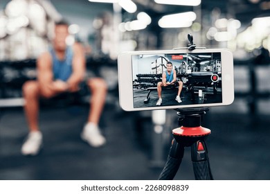 Gym, social media and fitness influencer with phone live streaming workout for interactive multimedia broadcast. Vlog, man filming arm exercise and training coach video recording online blog tutorial - Powered by Shutterstock