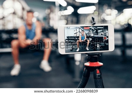 Gym, social media and fitness influencer with phone live streaming workout for interactive multimedia broadcast. Vlog, man filming arm exercise and training coach video recording online blog tutorial