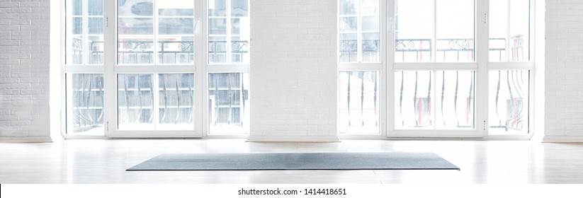 Gym White Interior With Black Yoga Mat, Big Windows, No People. Copy Space