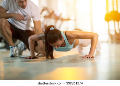 
Gym woman doing push ups with assisting her personal trainer - Powered by Shutterstock