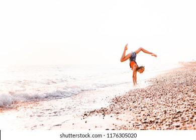 A gymnast in a beautiful pose against the background of the ocean. - Shutterstock ID 1176305020